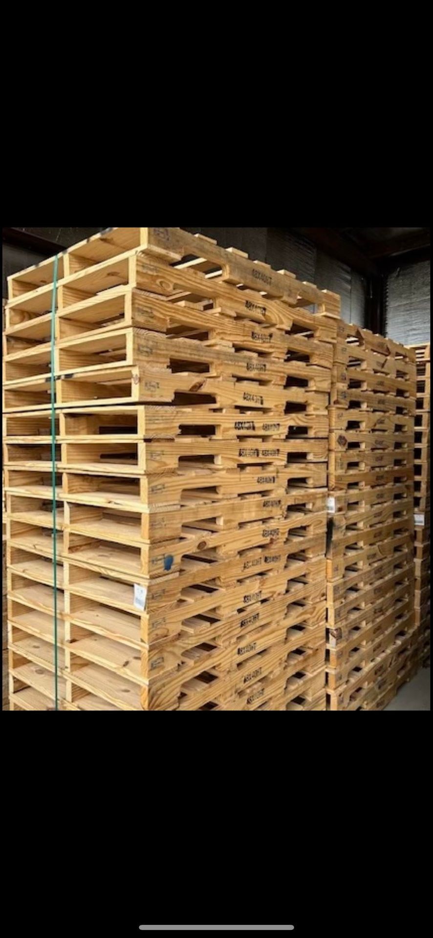 Stacks of wooden pallets in a warehouse, piled high and ready for shipping or storage.